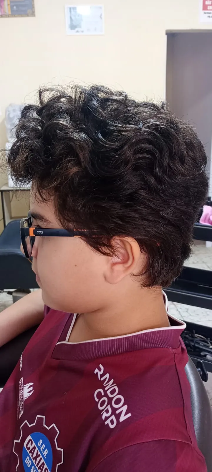Criança de óculos com cabelo cacheado, vista de lado