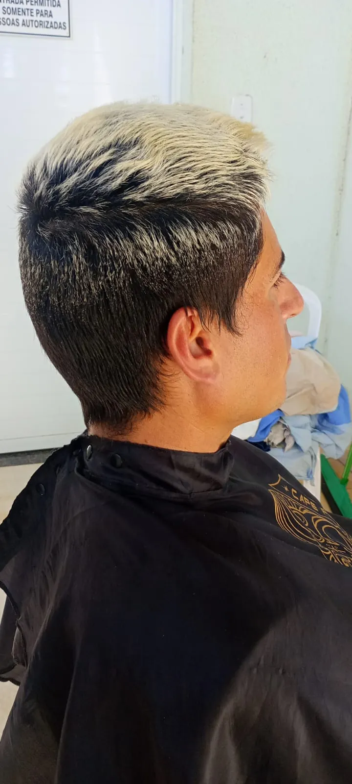 Corte masculino com topo platinado e laterais baixas, cliente de capa Gerryr